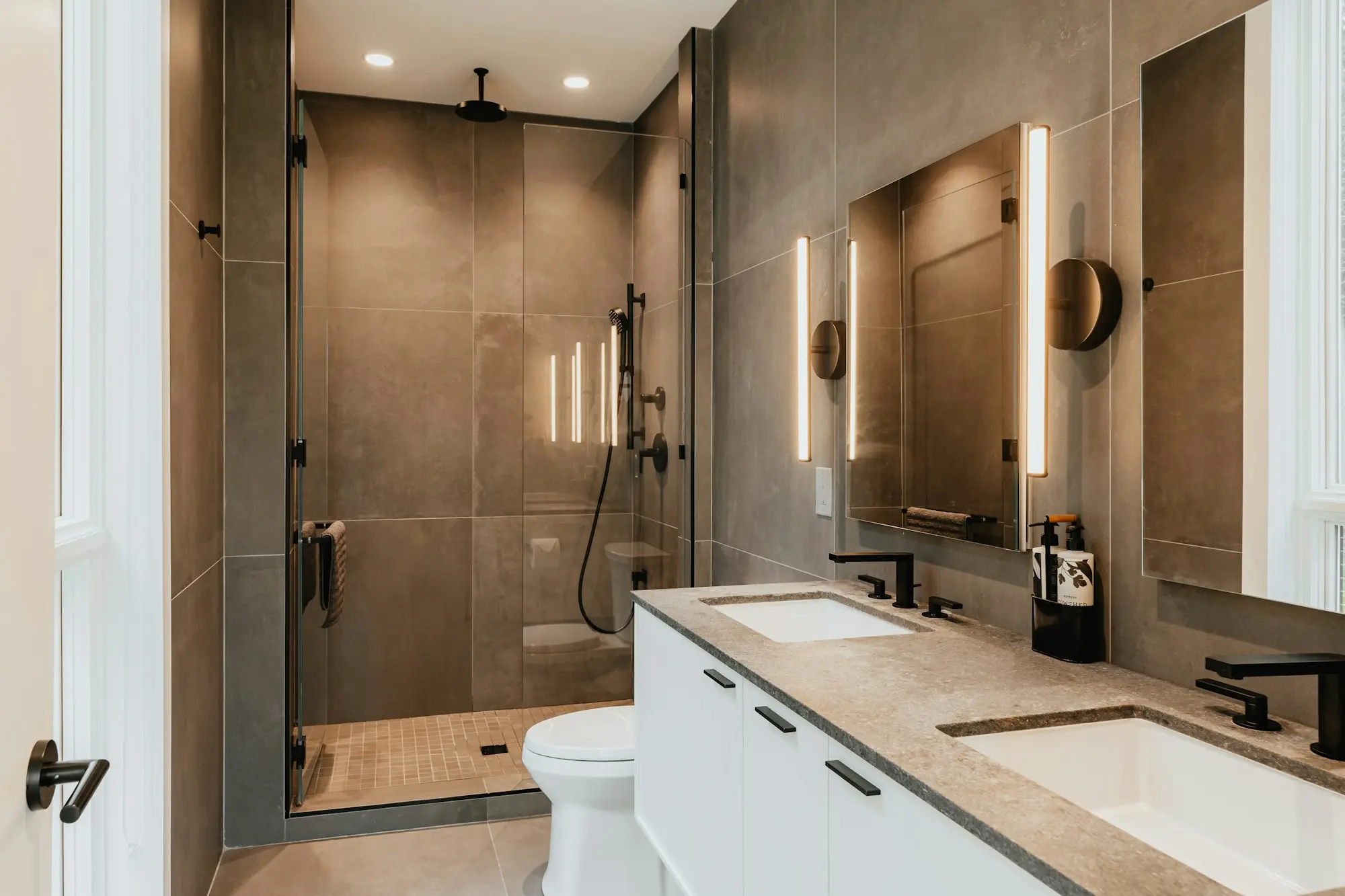 Contemporary bathroom in warm stone and timber with a walk-in shower, wall-hung WC and a double washbasin vanity